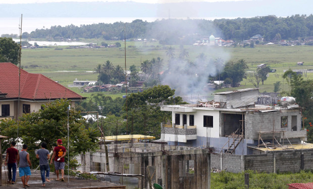 Residents watch a house that caught fire when the government troops continue to battle with Muslim militants who lay siege in Marawi city in southern Philippines Thursday, May 25, 2017. Army tanks packed with soldiers rolled into the southern Philippine city Thursday to try to restore control after ISIS-linked militants launched a violent siege that sent thousands of people fleeing for their lives and raised fears of extremists gaining traction in the country. (AP Photo/Bullit Marquez)