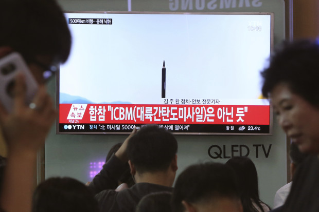 People watch a TV news program showing a file image of a missile launch conducted by North Korea, at the Seoul Railway Station in Seoul, South Korea, Sunday, May 21, 2017. North Korea on Sunday fired a midrange ballistic missile, U.S. and South Korean officials said, in the latest weapons test for a country speeding up its development of nuclear weapons and missiles. The letters read: "It does not seem to be an ICBM missile." (AP Photo/Ahn Young-joon)
