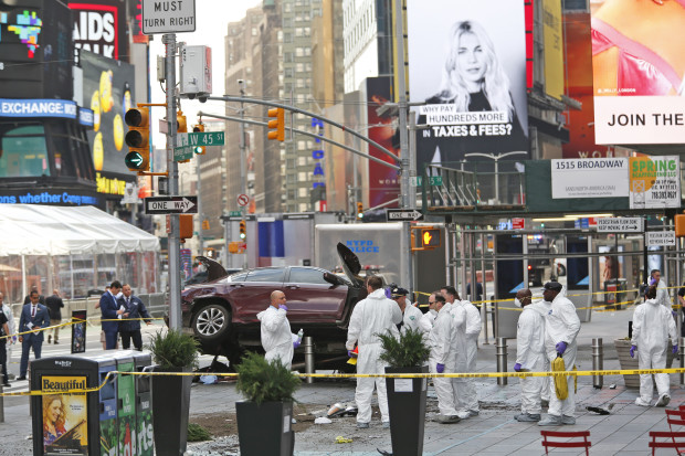 Police officers in protective clothes look over evidence at the scene of a fatal car crash, where a man steered his car onto a sidewalk and mowed down pedestrians, in Times Square, New York, Thursday, May 18, 2017. (AP Photo/Seth Wenig)
