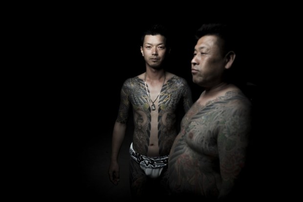In this picture taken on May 20, 2017, men pose for photographs showing their "Irezumi" Japanese traditional tattoos related to the Yakuza's universe, during the Sanja Matsuri festival in Tokyo. Over 1.5 million people flocked to Tokyo's Asakusa district during the three-day annual festival, which heralds the coming of summer in the Japanese capital. / AFP PHOTO / FRED DUFOUR