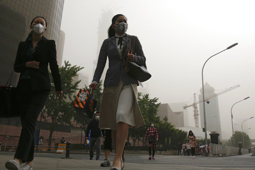 Office workers wearing face masks walk on a street as Beijing is hit by polluted air and sandstorm Thursday, May 4, 2017. Authorities in Beijing issued a blue alert on air pollution as sandstorm swept through the Chinese capital city on Thursday morning. AP
