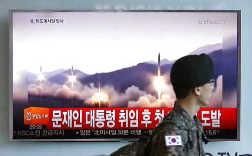 A South Korean army soldier walks by a TV news program showing a file image of missiles being test-launched by North Korea, at the Seoul Railway Station in Seoul, South Korea, Sunday, May 14, 2017. North Korea on Sunday test-launched a ballistic missile that landed in the Sea of Japan, the South Korean, Japanese and U.S. militaries said. The launch is a direct challenge to the new South Korean president elected four days ago and comes as U.S., Japanese and European navies gather for joint war games in the Pacific. The signs read: "The first provocation since the inauguration of President Moon Jae-in." AP