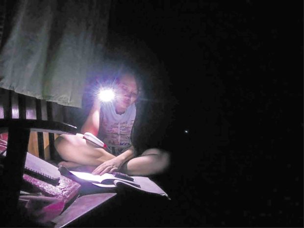 The power shortage now gripping Bohol is prompting residents  to cope, like using flashlights to read books and finish homework like what this student in Tagbilaran City is doing. —LEO UDTOHAN