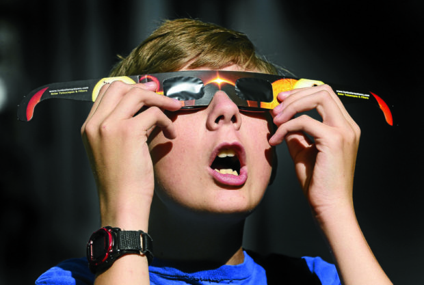 ECLIPSE WATCH Colton Hammer tries out his new eclipse glasses he bought from the Clark Planetarium in Salt Lake City in preparation for Monday’s solar eclipse visible in North America. —AP
