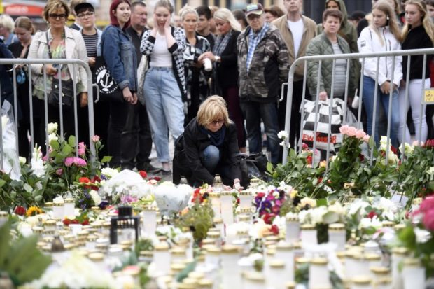Candles and flowers are left at the makeshift memorial by well wishers for the victims of Friday's stabbings at the Turku Market Square, Finland on August 19, 2017. AFP