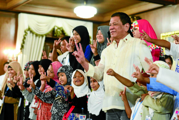 VISITING ‘TATAY DIGONG’ President Duterte and 35 children from war-ravaged Marawi City give the peace sign as they pose for pictures during the kids’ visit to Malacañang on Tuesday. —MALACAÑANG PHOTO