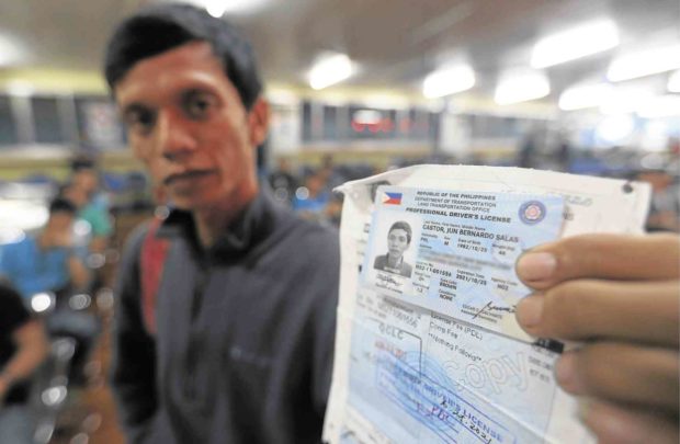 An applicant shows off the new and improved driver’s license which the LTO started issuing on Tuesday. —EDWIN BACASMAS