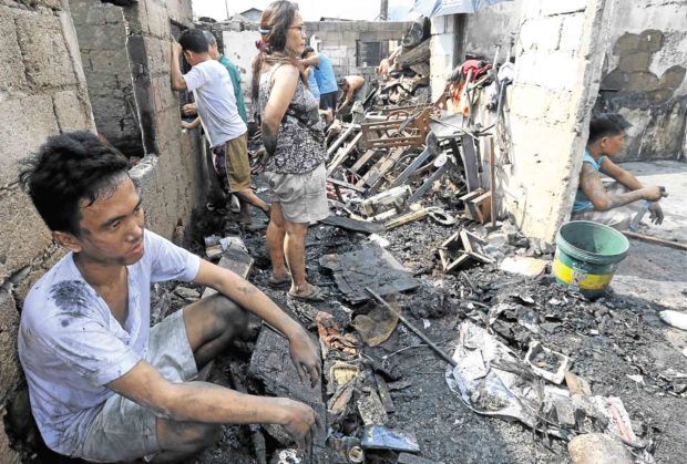 Residents look at the remains of their houses after a big fire hit Agham Road in Quezon City on Monday night, displacing 60 families.  —EDWIN BACASMAS