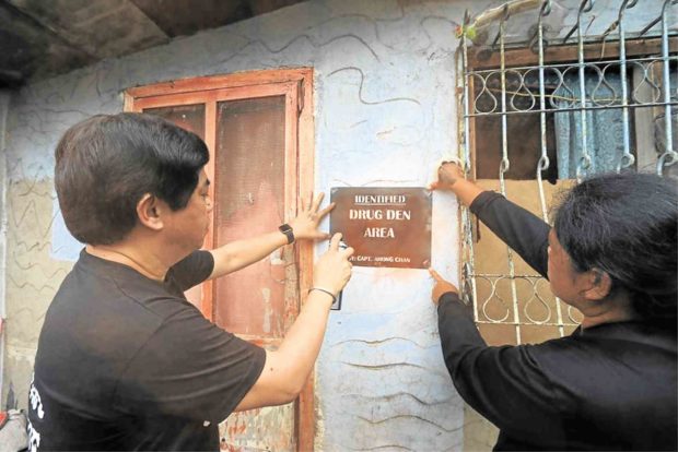 SHAME CAMPAIGN Village chief Junard Chan (left) helps install a sign marking a suspected drug den in Barangay Pajo in Lapu-Lapu City, Cebu. —NORMAN V. MENDOZA/CEBU DAILY NEWS