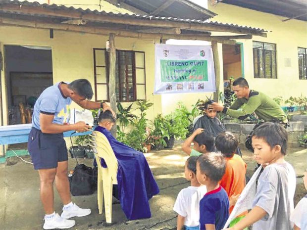 A militiaman from the Ilocos region offers free haircut to students in Dasol town, Pangasinan. —YOLANDA SOTELO
