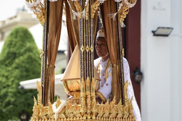 One of the royal doctors holds an urn containing the ashes of the late Thai king Bhumibol Adulyadej atop a royal chariot during the funeral procession to transport his ashes from the Royal Crematorium to the Grand Palace, in Bangkok on October 27, 2017. Thailand's new king picked bits of bone and ash from his father's remains on October 27 to be enshrined as royal relics, after the cremation of the late King Bhumibol Adulyadej capped an extravagant funeral that brought the nation to a standstill.  / AFP PHOTO / Lillian SUWANRUMPHA