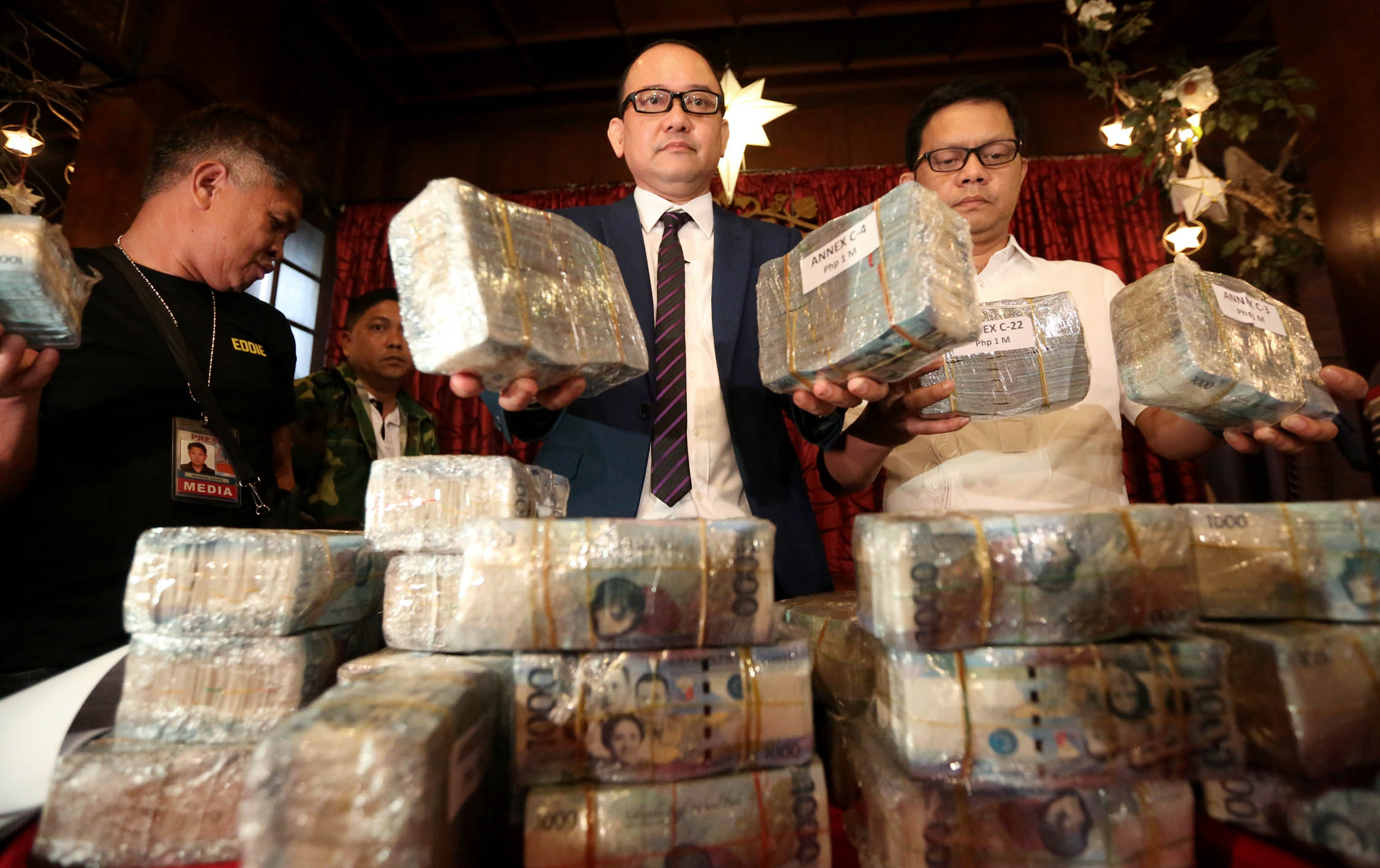 Former Deputy Immigration Commissioners Al Argosino and Michael Robles show the millions in cash they allegedly received from a gaming tycoon during a press conference in Manila. INQUIRER file photo / MARIANNE BERMUDEZ