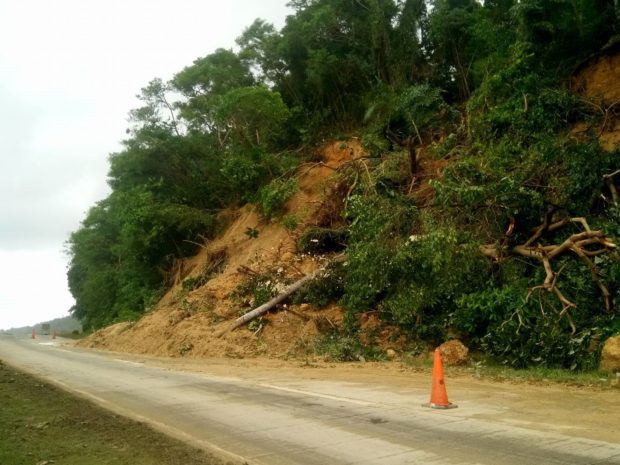 Motorists are cautioned to go slow when traveling along the national road in Barangay Cayam, Garcia Hernandez town, Bohol as mounds of earth and debris occupied half of the road following Tuesday’s landslide. - Leo Udtohan, Inquirer Visayas