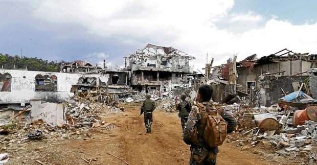 CITY IN RUINS Army soldiers walk to the front line against Islamic State-inspired terrorists among the war ruins in Marawi City. JEOFFREY MAITEM