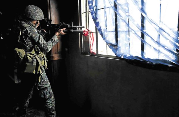 A government soldier takes position in a house once occupied by IS gunmen in Marawi City. The military has resorted to dropping leaflets to instruct civilians about what to do to flee to safer areas that had already been cleared by the Army. —JEOFFREY MAITEM