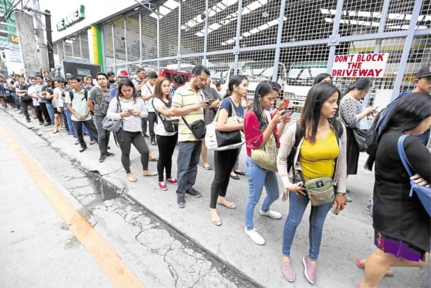 Metro Rail Transit 3 passengers cool their heels as they wait in line to enter North Avenue station in Quezon City. —NIÑO JESUS ORBETA