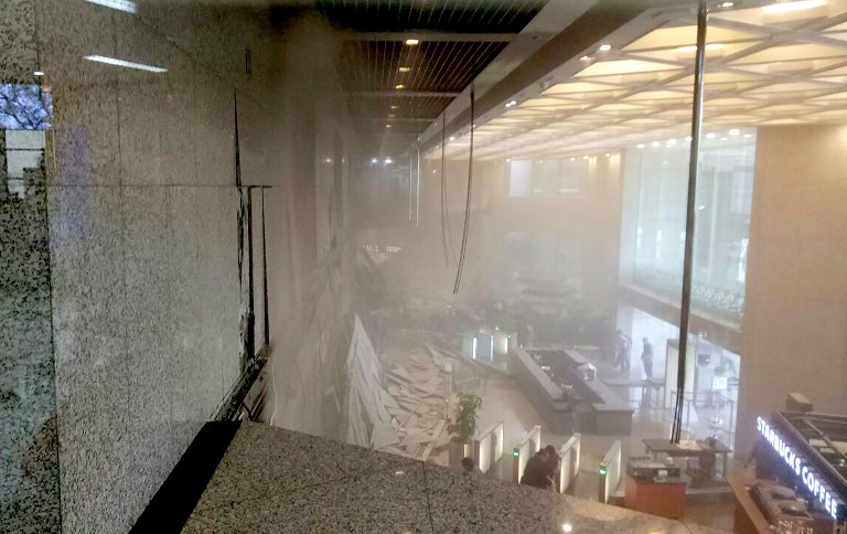 This photo received from Amailia Putri Hasniawati via WhatApp shows dust still clouding the lobby after an internal balcony collapsed at Indonesia's stock exchange in Jakarta on January 15, 2018. A floor at Indonesia's stock exchange collapsed into the building's lobby on January 15, injuring an unknown number of people, according to media reports. / AFP PHOTO / AMAILIA PUTRI HASNIAWATI