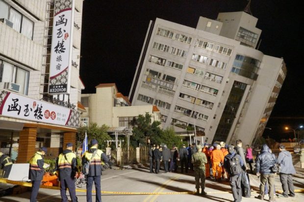 Rescue workers block off the area to search for survivors outside a building which tilted to one side after its foundation collapsed in Hualien after a strong 6.4-magnitude quake rocked eastern Taiwan early on February 7, 2018. The 6.4-magnitude earthquake on the east coast of Taiwan has left two dead and more than 200 injured, the government said on February 7, after buildings crumbled and trapped people inside. / AFP PHOTO / Paul YANG