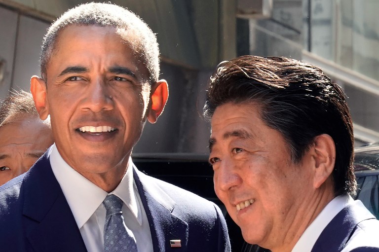 Former US president Barack Obama (L) is greeted by Japan's Prime Minister Shinzo Abe in front of a sushi restaurant in the Ginza shopping district of Tokyo on March 25, 2018.  / AFP PHOTO / POOL / Shizuo Kambayashi