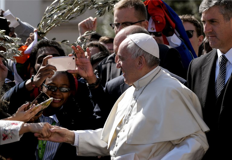 Pope Francis shakes hands with faithful at the end of the Palm Sunday mass in St. Peter's square on March 25, 2018 at the Vatican. Palm Sunday marks the sixth and last Sunday of the Christian Holy month of Lent and the beginning of Holy Week.  / AFP PHOTO / Marco BERTORELLO
