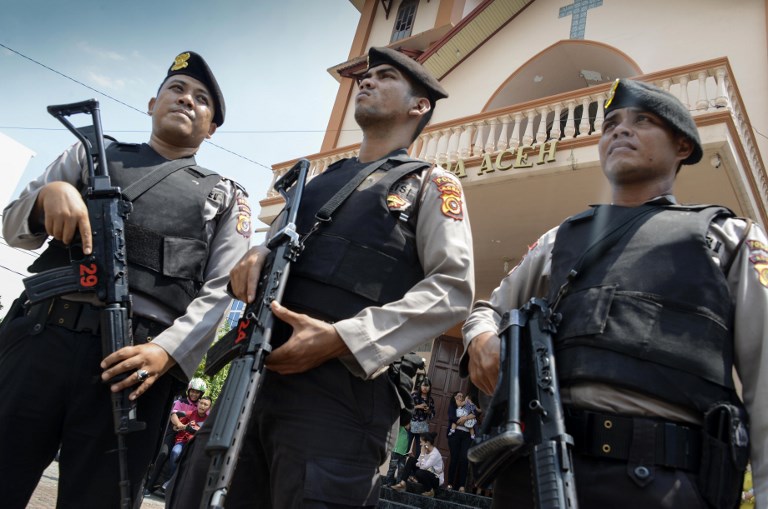 Police stand guard outside a church in Banda Aceh on May 13, 2018 following attacks on churches in Surabaya, East Java.  A wave of blasts, including a suicide bombing, struck churches in Indonesia on May 13, killing at least nine and wounding dozens of others in the deadliest attack in years to strike the world's biggest Muslim-majority country. / AFP PHOTO / CHAIDEER MAHYUDDIN