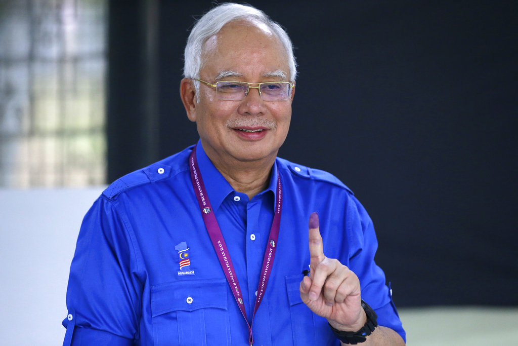 FILE - In this May 9, 2018, file photo, then Malaysian Prime Minister Najib Razak shows his finger marked with ink after voting at his hometown in Pekan, Pahang state, Malaysia. After 60 years of uninterrupted National Front rule, many Malaysians are optimistic they are ushering in an era of reform that echoes the democratic transformation of giant neighbor Indonesia two decades earlier. The difference, they hope, is that it will continue to be accomplished without setting their multiethnic country in flames. A grouping of progressive Southeast Asian lawmakers has hailed Najib’s defeat as a “bright spot amid dark times” of rising authoritarianism across the region. (AP Photo/Aaron Favila)