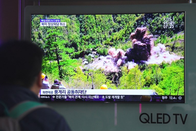 People watch a television news showing a picture of the dismantling of North Korea's Punggye-ri nuclear test site, at a railway station in Seoul on May 25, 2018.  North Korea said it had fully demolished its only known nuclear test site on May 24, with a series of planned detonations that put the facility beyond further use.  / AFP PHOTO / Jung Yeon-je