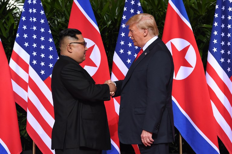 North Korea's leader Kim Jong Un (L) shakes hands with US President Donald Trump (R) at the start of their historic US-North Korea summit, at the Capella Hotel on Sentosa island in Singapore on June 12, 2018. Donald Trump and Kim Jong Un have become on June 12 the first sitting US and North Korean leaders to meet, shake hands and negotiate to end a decades-old nuclear stand-off. / AFP PHOTO / SAUL LOEB