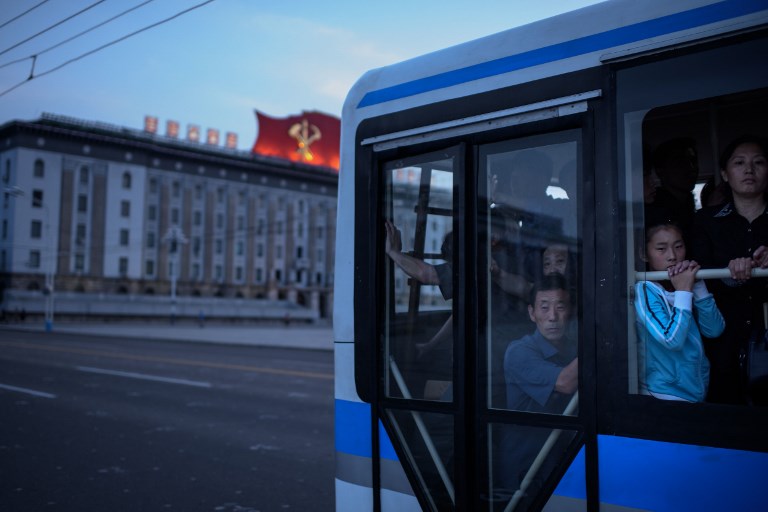 In a photo taken on June 16, 2018 commuters ride a bus through Kim Il Sung square in Pyongyang.  Donald Trump dangled the carrot of foreign investment in front of North Korean leader Kim Jong Un at their nuclear summit, but analysts say few will want to put money into one of the highest-risk business environments in the world. / AFP PHOTO / Ed JONES / TO GO WITH AFP STORY: NKorea-Economy-Diplomacy-Nuclear; Focus by Sebastien BERGER