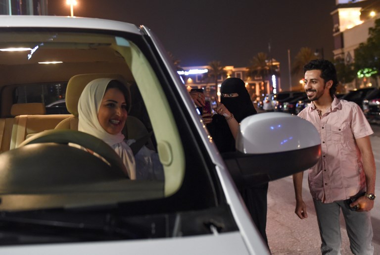 A Saudi woman films and shows support to Samar Al-Moqren (L) who drives her car through the streets of the Saudi capital Riyadh for the first time just after midnight, June 24, 2018, when the law allowing women to drive took effect.  Saudi Arabia will allow women to drive from June 24, ending the world's only ban on female motorists, a historic reform marred by what rights groups call an expanding crackdown on activists. The move, which follows a sweeping crackdown on women activists who long opposed the ban, is part of Crown Prince Mohammed bin Salman's wide-ranging reform drive to modernise the conservative petrostate.   / AFP PHOTO / FAYEZ NURELDINE