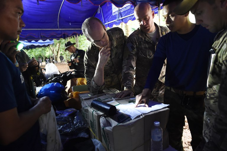 A Thai military officer (2nd-R) briefs US military personnel at a command outpost in Khun Nam Nang Non Forest Park near Than Luang cave in Chiang Rai province on June 28, 2018 during rescue operation for a missing children's football team and their coach. Rescuers battled heavy rain as they struggled to drain the flooded tunnels in the Tham Luang cave where the youngsters, aged 11 to 16, and their coach have been stuck since June 23.  / AFP PHOTO / LILLIAN SUWANRUMPHA