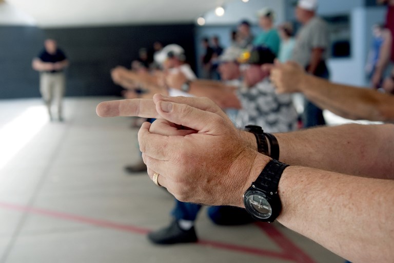 School teachers and administrators simulate firing their guns during a three-day firearms course offered by FASTER Colorado at Flatrock Training Center in Commerce City, Colorado on June 27, 2018.  FASTER Colorado has been sponsoring firearms training to Colorado teachers and administrators since 2017. Over 100 Colorado teachers and administrators have participated in the course. Colorado is one of approximately 30 states that allow firearms within school limits, and an estimated 25 school districts in Colorado allow teachers and administrators to carry concealed firearms. / AFP PHOTO / Jason Connolly