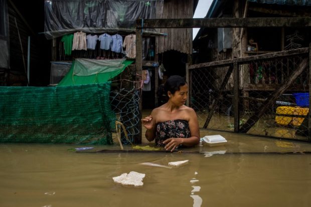 A woman walks through floodwaters in the Bago region, some 68 km away from Yangon, on July 29, 2018. Heavy monsoon rains have pounded Karen state, Mon state and Bago region in recent days and show no sign of abating, raising fears that the worst might be yet to come. / AFP PHOTO / Ye Aung THU