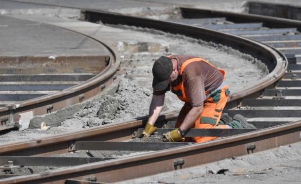 germany A worker applies cement to tramway tracks at a construction site in Berlin on April 18, 2018.  / AFP PHOTO / John MACDOUGALL