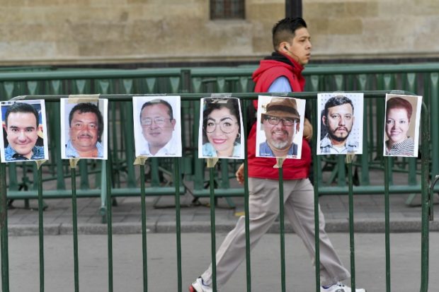 A man walks past pictures of members of the press during a protest against the murder or disappearance of more than 140 journalists and photojournalists in Mexico since 2000, in front of the National Palace in Mexico City on June 1, 2018. Racked by violent crime linked to the multibillion-dollar narcotics trade, Mexico posted a record number of homicides last year: 25,339. That included at least 11 murdered journalists, making the country the deadliest in the world for the profession after Syria, according to Reporters Without Borders.  / AFP PHOTO / Yuri CORTEZ