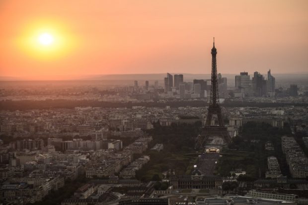 (FILES) This file photo taken on July 14, 2018 from the panoramic observatory of the Montparnasse Tower (Tour Montparnasse) shows the sunset over Paris and the Eiffel Tower, few hours before the traditional Bastille day fireworks. Eiffel Tower workers are planning to strike this week over a new access policy for visitors which they say is generating "monstrous" waits at the famous tourist landmark, union officials said on July 30. Since early July the monument has set aside half of daily tickets for people who buy them in advance on the internet and choose a scheduled time for their visit.  / AFP PHOTO / Lucas BARIOULET