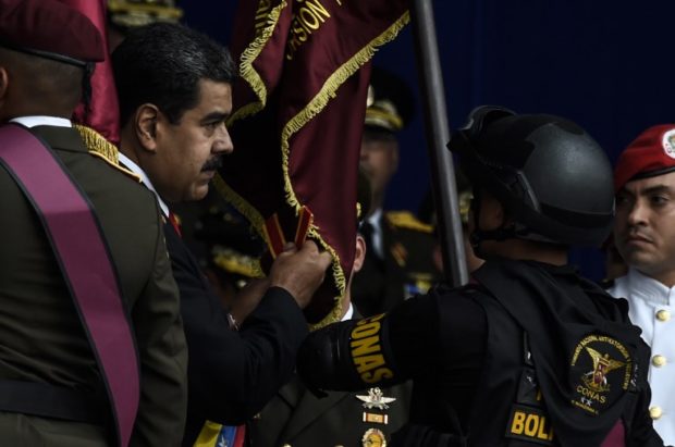 Venezuelan President Nicolas Maduro (L) attends a ceremony to celebrate the 81st anniversary of the National Guard in Caracas on August 4, 2018. Maduro was unharmed after an exploding drone "attack", the minister of communication Jorge Rodriguez said following the incident, which saw uniformed military members break ranks and scatter after a loud bang interrupted the leader's remarks and caused him to look to the sky, according to images broadcast on state television. / AFP PHOTO / Juan BARRETO