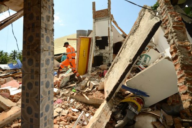 Members of the National Agency for Disaster Management search for victims at a damaged house at Pemenang village in northern Lombok in West Nusa Tenggara province on August 7, 2018, two days after the area was struck by an earthquake. The shallow 6.9-magnitude quake killed at least 98 people and destroyed thousands of buildings in Lombok on August 5, just days after another deadly tremor surged through the holiday island and killed 17. / AFP PHOTO / SONNY TUMBELAKA