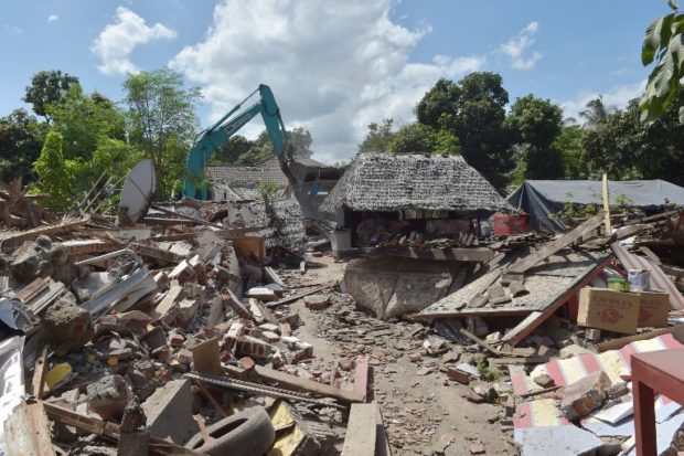 Workers take down a damaged shop with an excavator in an earthquake-hit area in Gangga on August 12, 2018. An earthquake on the Indonesian island of Lombok has killed 387 people, authorities said on August 11, adding hundreds of thousands of displaced people were still short of clean water, food and medicine nearly a week on. / AFP PHOTO / ADEK BERRY indonesia