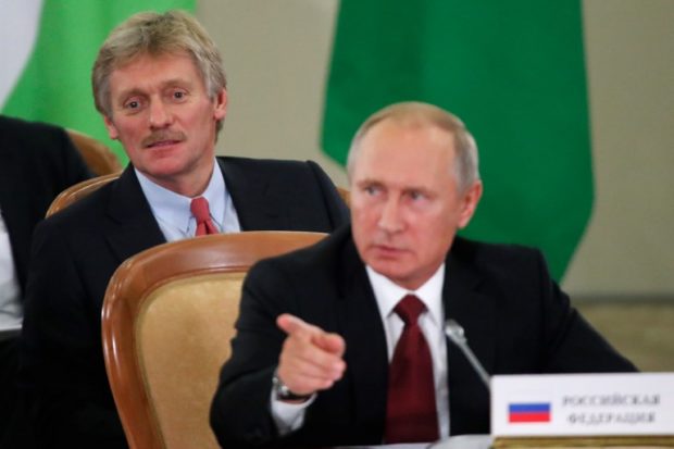 Russia's President Vladimir Putin (front) and Kremlin spokesman Dmitry Peskov attend a session of the Council of Heads of the Commonwealth of Independent States (CIS) in Sochi on October 11, 2017.  / AFP PHOTO / POOL / MAXIM SHEMETOV