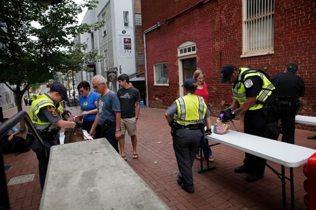 CHARLOTTESVILLE, VA - AUGUST 11: Members of the Virginia State Police search the belongings of people entering the downtown mall area of the city August 11, 2018 in Charlottesville, Virginia. Charlottesville has been declared in a state of emergency by Virginia Gov. Ralph Northam as the city braces for the one year anniversary of a deadly clash between white supremacist forces and counter protesters over the potential removal of Confederate statues of Robert E. Lee and Jackson. A "Unite the Right" rally featuring some of the same groups is planned for tomorrow in Washington, DC. Win McNamee/Getty Images/AFP