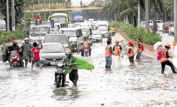 TRASH FLOOD Workers collect trash dumped into Roxas Boulevard by waves whipped up by the southwest monsoon enhanced by Tropical Storm “Karding.”—MARIANNE BERMUDEZ