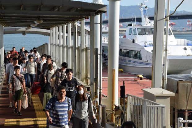 Passengers stranded overnight at the Kansai International Airport due to typhoon Jebi arrive at the Kobe port by boat on September 5, 2018. The toll in the most powerful typhoon to hit Japan in a quarter century rose on September 5 to nine, with thousands stranded at a major airport because of storm damage. / AFP PHOTO / JIJI PRESS / JIJI PRESS / Japan OUT