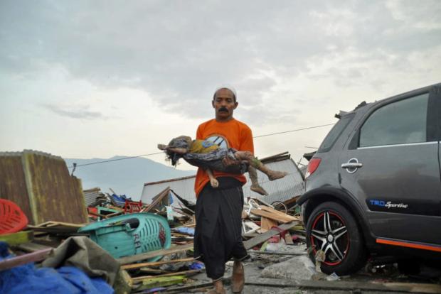 Man carries dead child in tsunami aftermath in Indonesia