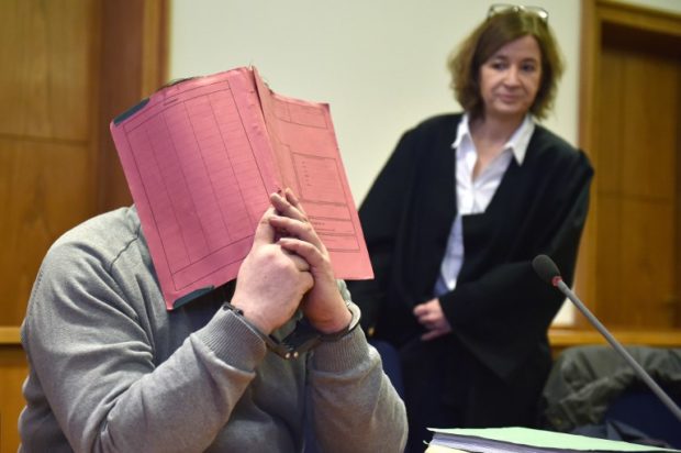 (FILES) In this file photo taken on February 26, 2015 German former male nurse Niels Hoegel hides his face behind a folder as he waits next to his lawyer Ulrike Baumann (R) for the opening of another session of his trial at a court in Oldenburg, northwestern Germany. - German nurse Niels Hoegel, already serving a lengthy term for previous killings, will go on trial before anguished relatives on October 30, 2018 over the murders of around 100 more people -- a spree prosecutors say is unprecedented in the post-war period. (Photo by CARMEN JASPERSEN / DPA / AFP) / Germany OUT