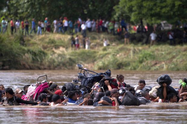 Central American migrants wading in river