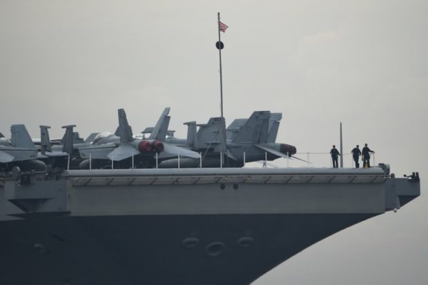 jet US sailors stand next to F/A-18 Super Hornets parked on the bow of the nuclear-powered aircraft carrier USS Ronald Reagan (CVN-76) anchored off Manila bay on June 26, 2018. - A US aircraft carrier visited the Philippines on June 26, the third such call in four months, as its admiral hailed America's "enduring presence" in a region where China's military build-up had raised tensions. (Photo by TED ALJIBE / AFP)