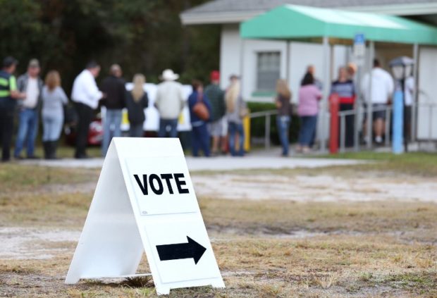 Voters wait in a queue to cast their ballots in the presidential election at a polling station in Christmas, Florida on November 8, 2016. - Polling stations opened Tuesday as the first ballots were cast in the long-awaited election pitting Hillary Clinton against Donald Trump. (Photo by Gregg Newton / AFP)