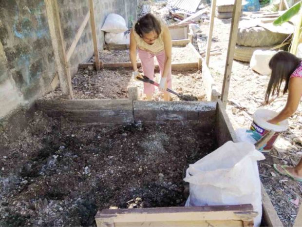 SPADEWORK Evangeline “Tata” Domine (center) and her backyard compost heap at United Parañaque Subdivision 5 —CONTRIBUTED PHOTO