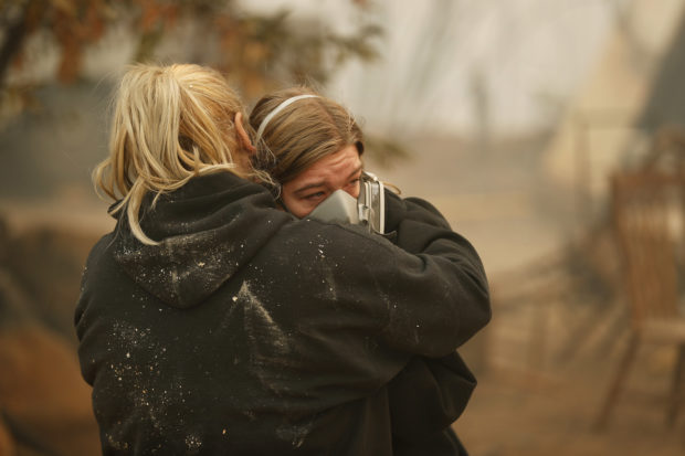 Krystin Harvey, left, comforts her daughter Araya Cipollini at the remains of their home burned in the Camp Fire, Saturday, Nov. 10, 2018, in Paradise, Calif. The blaze that started Thursday outside the hilly town of Paradise has grown and destroyed more than 6,700 buildings, almost all of them homes, making it California's most destructive wildfire since record-keeping began. But crews have made gains and the fire is partially contained, officials said Saturday. (AP Photo/John Locher)